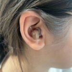 Real ear fit view of the beige AXON K-188 Hearing Aid worn discreetly in the ear.