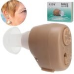 AXON K-86 in-ear hearing aid with transparent ear tip, shown being worn in the ear, alongside its green packaging box.